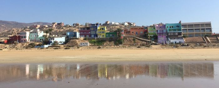 Reflection of buildings on lake against clear sky
