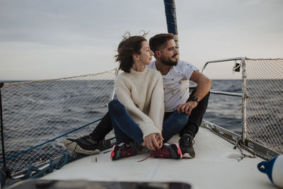 Girlfriend and boyfriend sitting on sailboat during vacation