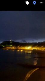 Illuminated beach against sky at night