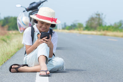 Full length of man using mobile phone while sitting on road
