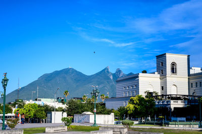 Road by buildings against blue sky