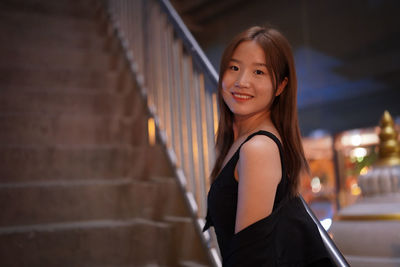 Portrait of young woman standing against wall