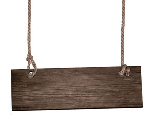 Close-up of swing hanging on rope against white background