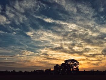 Silhouette of trees against cloudy sky