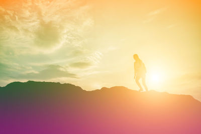 Silhouette man standing on mountain against sky during sunset