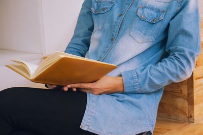 Midsection of man holding book at home