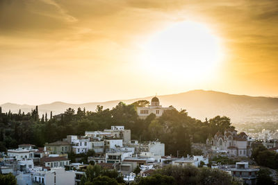 Houses in town against sky during sunset