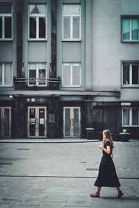 Full length of woman sitting outside building