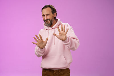 Midsection of man standing against pink background