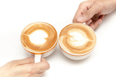 Cropped image of hand holding coffee cup against white background