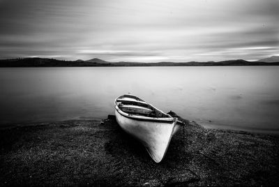 Boat moored on lake against sky