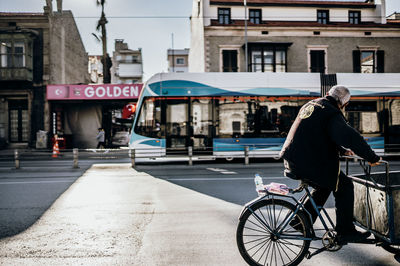 Rear view of man riding bicycle on road