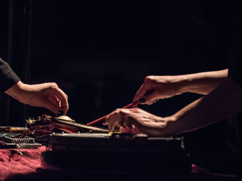 Cropped hands playing music against black background