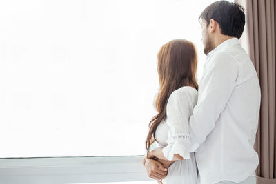 Rear view of man and woman standing against white background