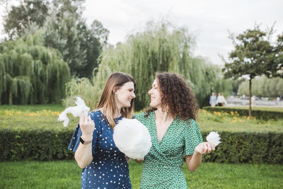 Smiling female friends eating large cotton candy at park