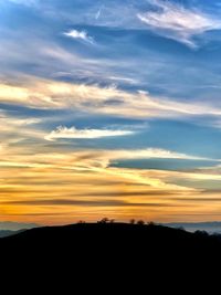 Silhouette landscape against dramatic sky during sunset