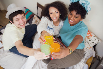 High angle view of mother and female friends sitting on bed at home