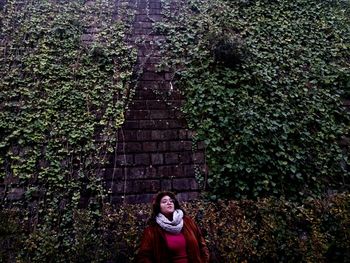 Young woman standing against plants