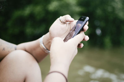 Midsection of woman using mobile phone outdoors
