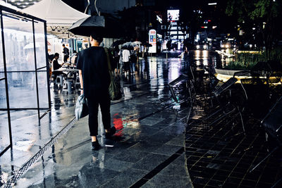People walking on wet street during rainy season