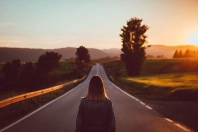 Rear view of man standing on road at sunset