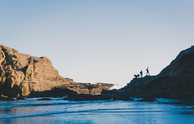 Rock formations by sea against clear sky