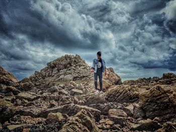 Full length of man standing on rock against sky