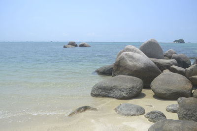 Rocks in sea against clear sky
