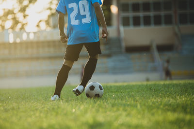 Low section of man playing soccer ball on field