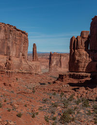 Low angle view of red sandstone rock formations against clear blue sky park avenue area arches park