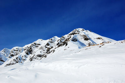 Scenic view of snowcapped mountains against blue sky