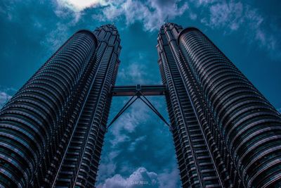 Low angle view of skyscrapers against cloudy sky