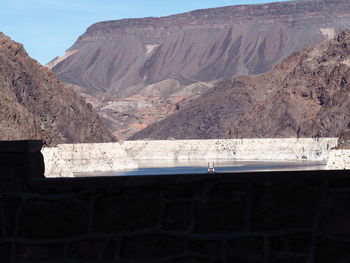 Scenic view of dam and mountains against sky
