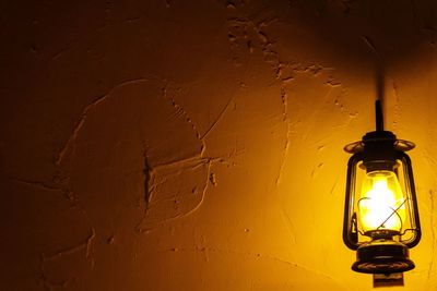 Close-up of illuminated light bulb against wall