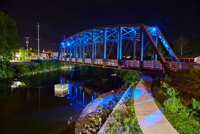 Illuminated bridge over river at night