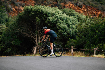 Rear view of man riding bicycle on road