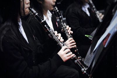 Midsection of women playing clarinet graduation ceremony