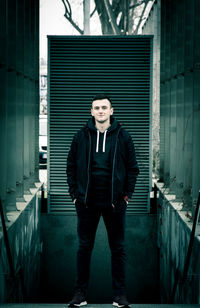 Portrait of young man standing against wall