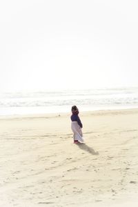 Rear view of man on beach against clear sky