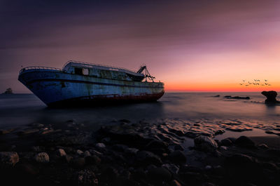 Scenic view of old boat at sea during sunset