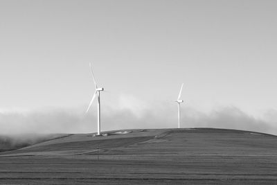 Windmills on field against sky