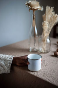 Cropped woman holding mug on table