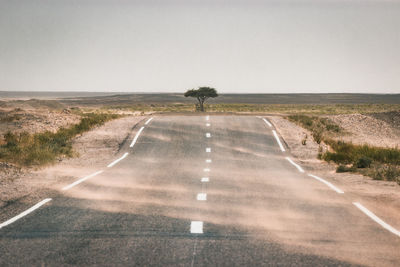 Road amidst field against sky