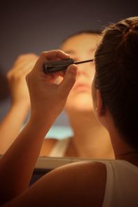 Rear view of young woman applying mascara