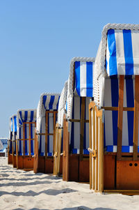 Hooded beach chairs against clear sky