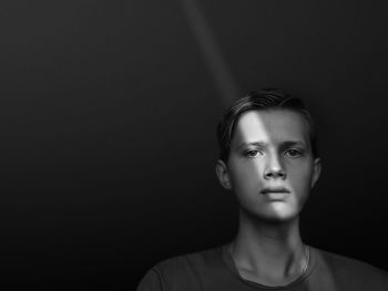 Portrait of serious young man standing against black background