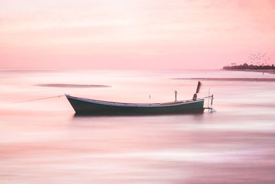 Ship moored in sea against sky during sunset