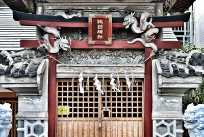 Text amidst dragon sculptures at shrine entrance