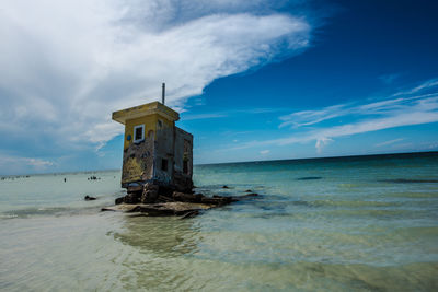 Built structure on beach by sea against sky