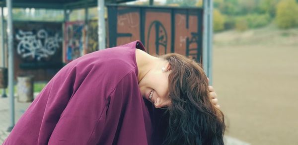 Portrait of smiling woman bending on footpath 